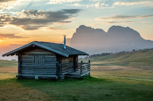 A small wooden hut surrounded by the beautiful Dolomites mountains during the sunset