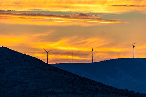 A mesmerizing view of windmills on top of evergreen mountains during a scenic sunset in Croatia