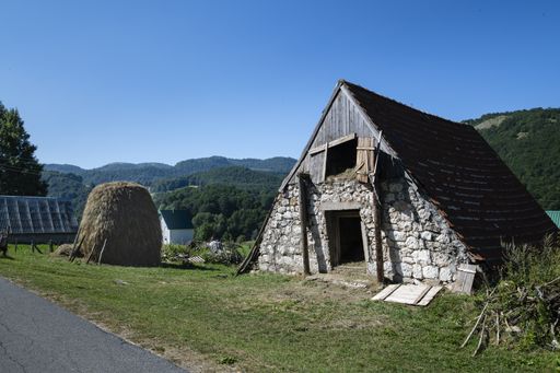A beautiful shot of a small triangular stone barn in a rural area and the sky in the background