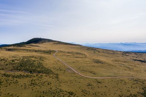 An autumn landscape of a grassy valley and a hiking road under the blue sky