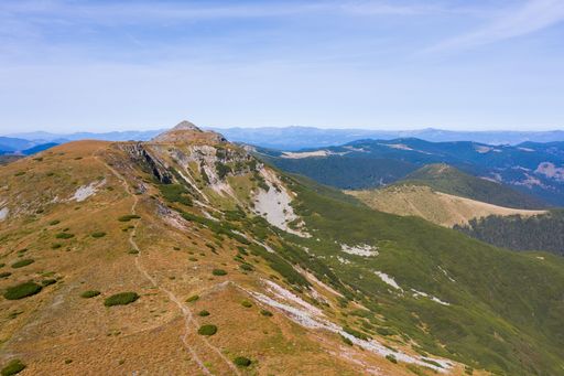 Stunning view of blue cloudy sky over layered mountain ranges and valley covered with vegetation on sunny day
