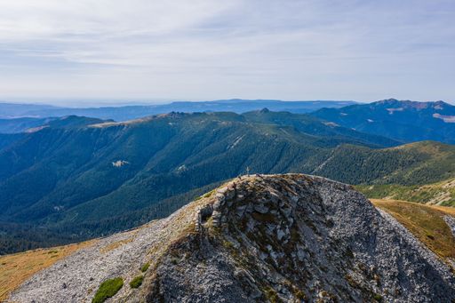 Stunning view of blue cloudy sky over layered mountain ranges and valley covered with vegetation on sunny day