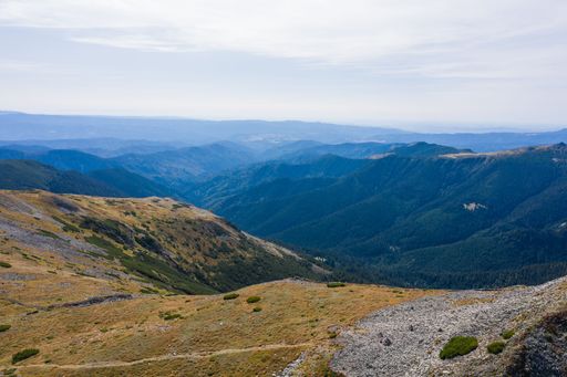 Stunning view of blue cloudy sky over layered mountain ranges and valley covered with vegetation on sunny day