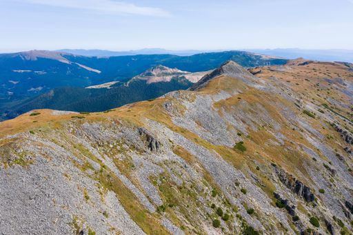 Stunning view of blue cloudy sky over layered mountain ranges and valley covered with vegetation on sunny day