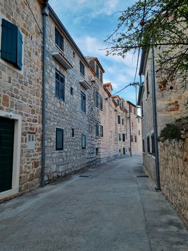 A vertical shot of concrete alley between rows of old stone buildings