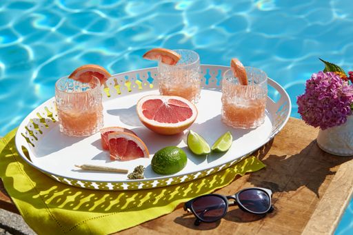A high angle closeup shot of a tray with grapefruit cocktails near the swimming pool