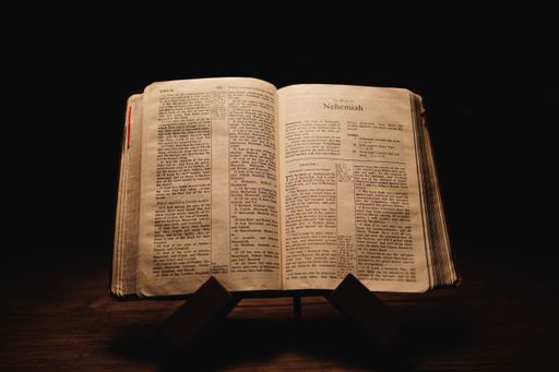 A closeup shot of a historic old Bible open on the Nehemiah pages on display in a dark room