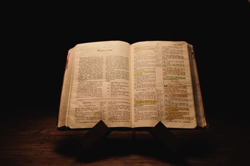 A closeup shot of a historic old Bible open on the Proverbs pages on display in a dark room