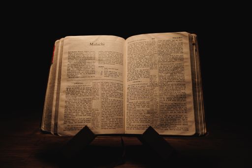A closeup shot of a historic old Bible open on the Malachi pages on display in a dark room