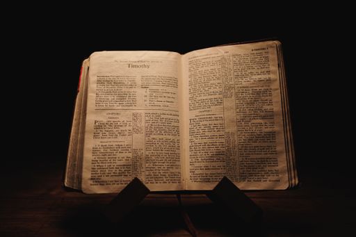 A closeup shot of a historic old Bible open on the Timothy pages on display in a dark room