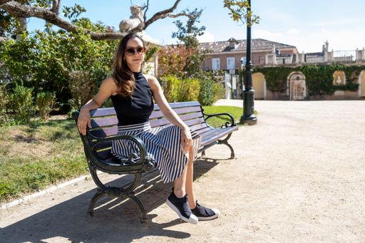 A Young fashionable woman with sunglasses in summer clothes sitting on a bench in the park relaxing