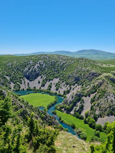 An aerial view of Krupa river in lush green valley surrounded by rocky hills