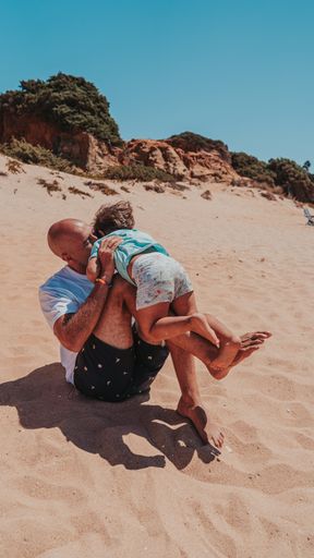 The dad and his son happily playing in the sandy beach