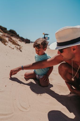 The father and his son happily playing in the sandy beach
