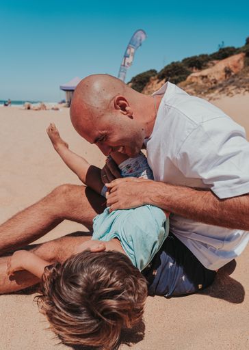 The father and his son happily playing in the sandy beach