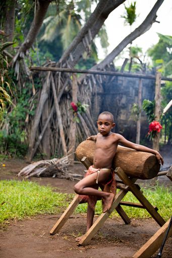 A tribal boy leaning against the log