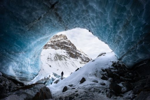 Blue textured ice cave exploration with a silhouette of a hiker in Arolla glacier, Valais Switzerland