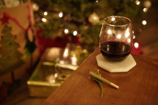 A high angle closeup shot of a marijuana blunt and a glass of cognac on a table on blurred background