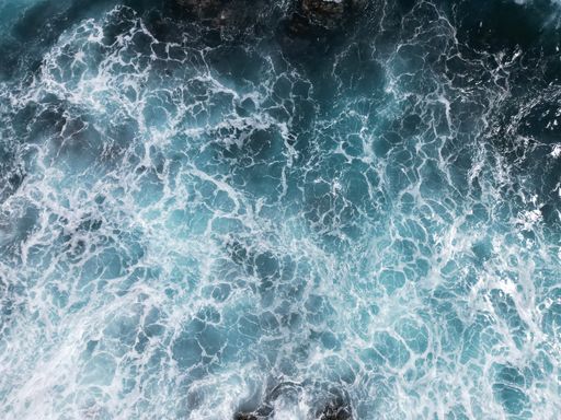A high angle shot of flowing waves and ripples on a sea surface