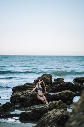 A sexy caucasian woman wearing a spotted swimsuit and posing on a beach