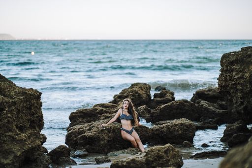 A sexy caucasian woman wearing a spotted swimsuit and posing on a beach