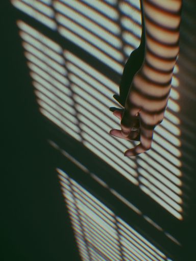 A vertical shot of a hand against a wall with shadows and lights casting on it - good for aesthetic background