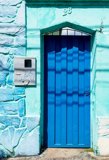 Blue house facade with mailbox. Blue metal door in a house with blue stone facade.