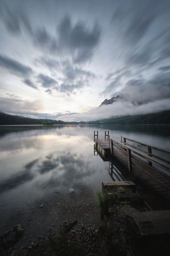 A vertical shot of a wooden pier at the shore of Lake Eibsee, Bavaria, Germany