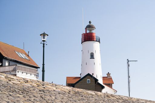 A low angle shot of a white lighthouse under the clear blue sky