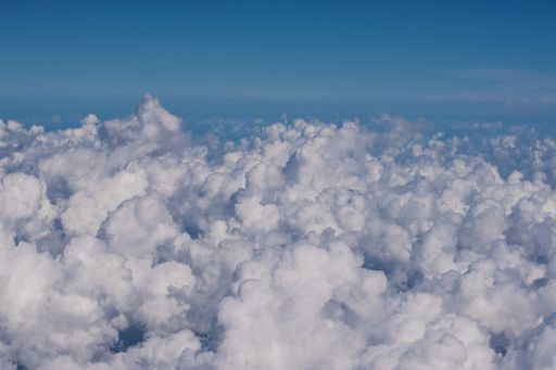 A vast cloudscape with whte, fluffy clouds seen from above