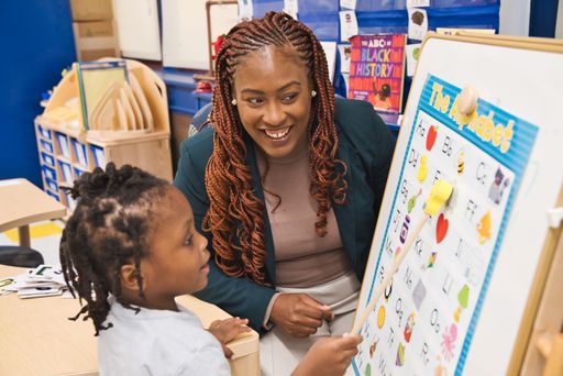 An African American Black teacher teaching young black student in the classroom
