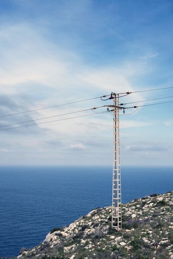 A vertical shot of an electric tower near the sea