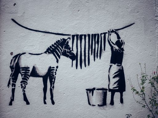 A graffiti painting of an old peasant woman and a zebra on a white wall in Nantes