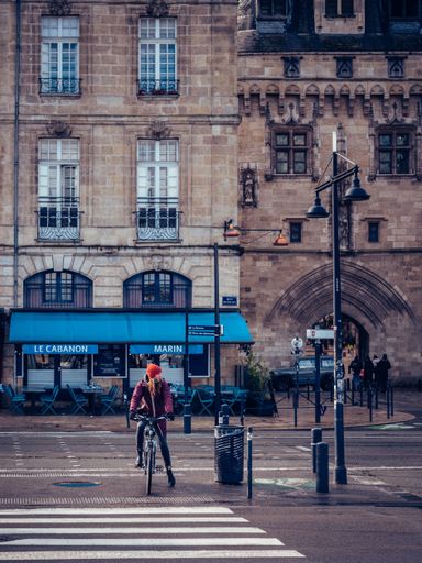 A vertical shot of a Caucasian female riding a bicycle on the streets of Nantes, France