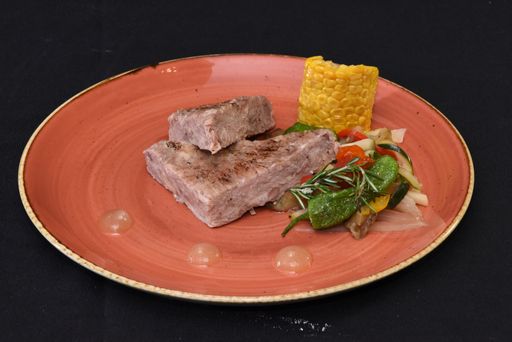 A closeup shot of steak with vegetables in a black background