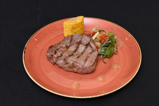A closeup shot of steak with vegetables in a black background