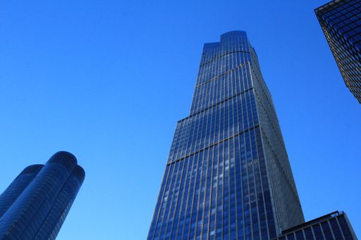 A low angle shot of a skyscraper with glass windows and the sky in the background