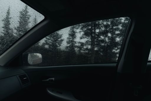 A view from a car window of rain drops out on a road under pikes peak  trees in Colorado