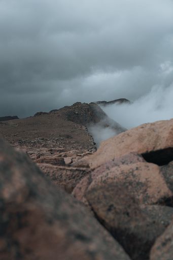 A foggy view over stones of pikes peak cliff in Colorado under a gray sky, vertical shot