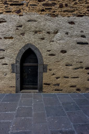A vertical shot of an antique door on a stone tower