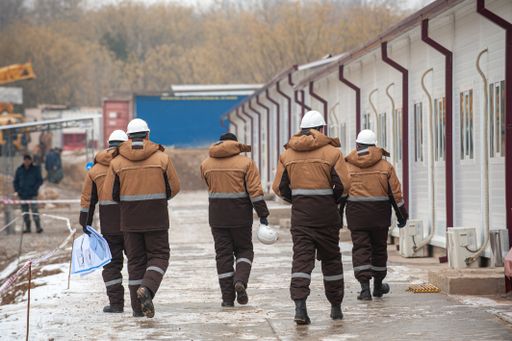 A back view of industrial construction workers wearing uniform on a cold weather
