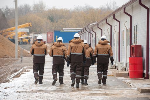 A beautiful shot of workers in special equipment and helmets with Oil and gas construction in the background