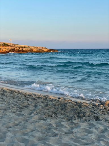 A vertical shot of the splashing waves of the sea at the sandy shore