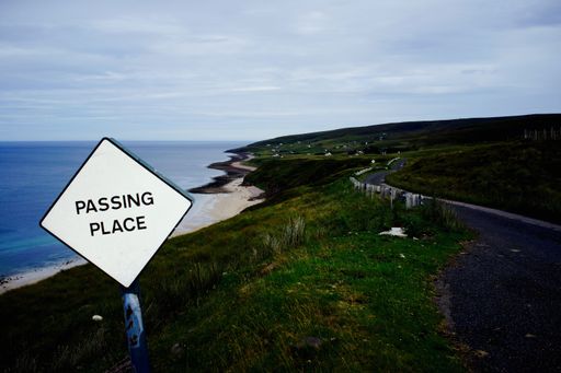 A passing place sign on the shore with a view of the sea on a rainy day