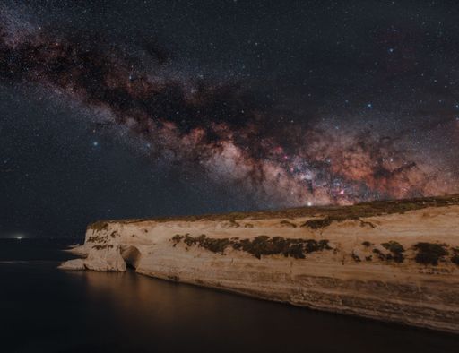 The beautiful view of the smooth sea with a cliff against the background of the Milky Way.