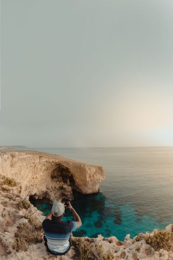 A young man sitting on an inland cave in Malta at sunrise.