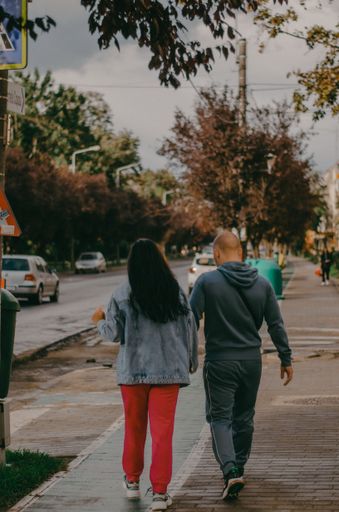 A vertical closeup shot of two people walking on the street on a sunny day