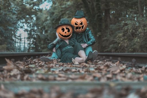 A closeup shot of a couple wearing pumpkins on their heads in the forest