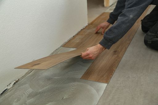 The worker installing the new vinyl tiles on the floor in the house