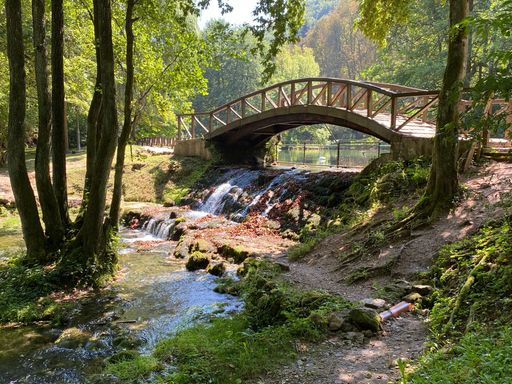 A bridge over a river flowing on a rocky surface in a park